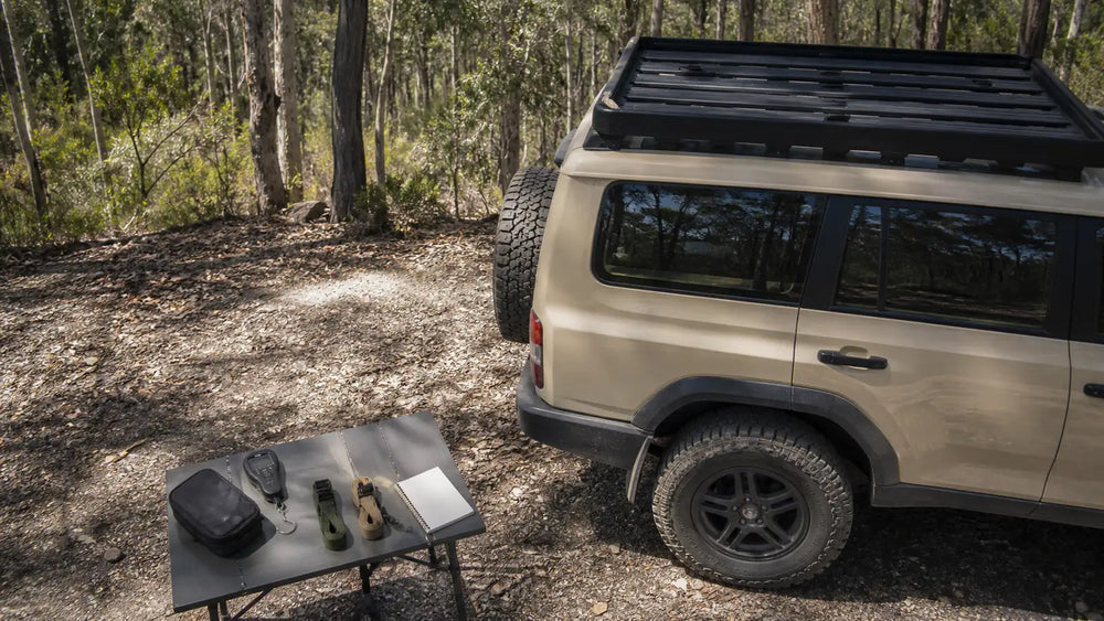 Roof-load planning beside a generic 4WD, with an empty platform, weighing scale and packing notes